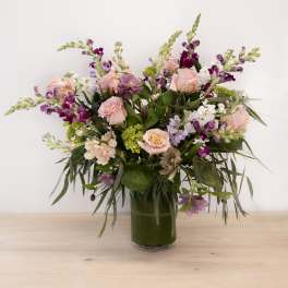 Mixed pink and purple flowers arranged in a glass vase