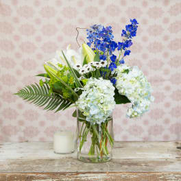 Blue and white floral arrangement in a clear glass vase