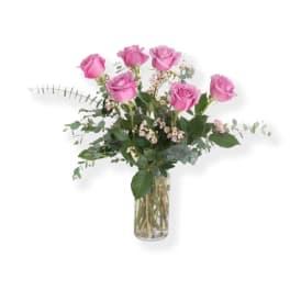 Pink roses arranged in a clear glass vase with airy greenery