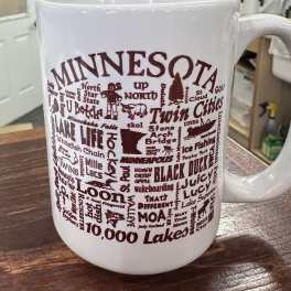 White ceramic mug with maroon Minnesota-themed text and graphics