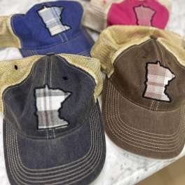 Four baseball caps with Minnesota-shaped patches arranged on a light surface.