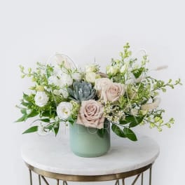 Pastel floral arrangement in a mint vase with roses and white blooms