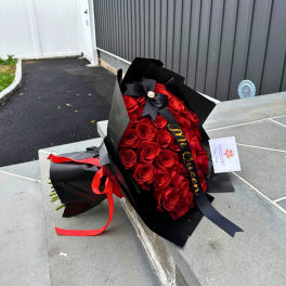 Bouquet of red roses wrapped in black paper with a ribbon