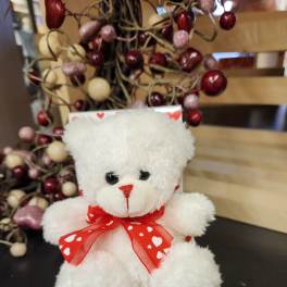 White teddy bear with a red heart ribbon in a Valentine display