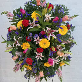 Large standing floral spray with mixed bright flowers on a black easel