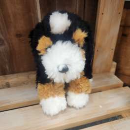 Fluffy tricolor stuffed dog sitting on wooden steps