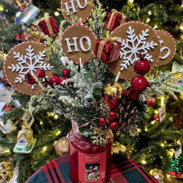 Christmas arrangement in a red candle jar with HO HO HO signs and ornaments