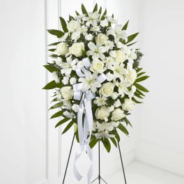 White floral standing spray with roses and lilies on an easel