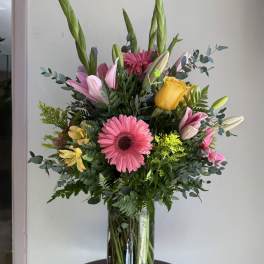 Mixed bouquet in a glass vase with pink, yellow, and white flowers