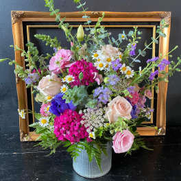 Mixed pink, purple, and white flowers in a ribbed metal container
