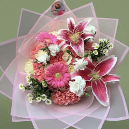 Hand-tied bouquet of pink lilies, gerbera daisies, carnations and white blooms in pink wrap