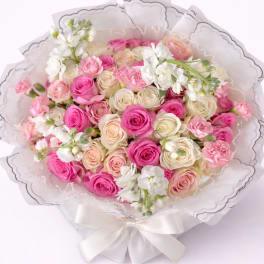 Bouquet of pink and cream roses with white flowers wrapped in white paper