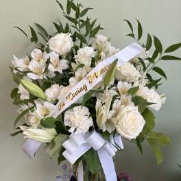 White floral sympathy arrangement in a glass vase with a memorial ribbon