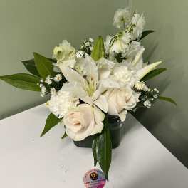 White roses and lilies arranged in a dark vase