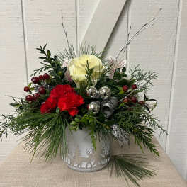 Holiday floral arrangement in a white metal container with red and white blooms