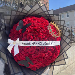 Large bouquet of red roses with a white ribbon and black wrap