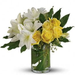 White lilies and yellow roses in a clear glass vase