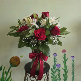 Bouquet of red roses and white lilies in a glass vase with a red ribbon