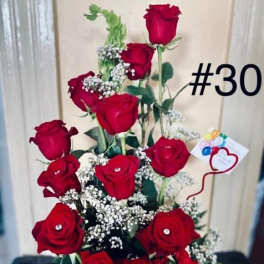 Tall arrangement of red roses with baby's breath in a white container