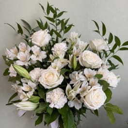 White roses and lilies arranged in a clear glass vase