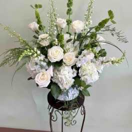 White roses and hydrangeas in a vase with tall green accents