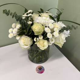 White roses and chrysanthemums in a glass vase with eucalyptus