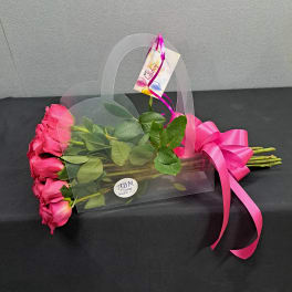 Pink roses in a clear gift bag with a bright ribbon and birthday tag