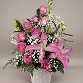 Pink roses and lilies arranged in a white basket