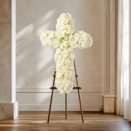 White floral cross on a stand in a bright room