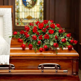 Red rose arrangement on a wooden casket in a chapel setting