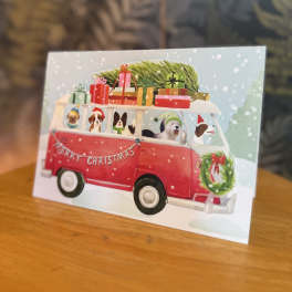 Christmas card with a red van carrying gifts and dogs