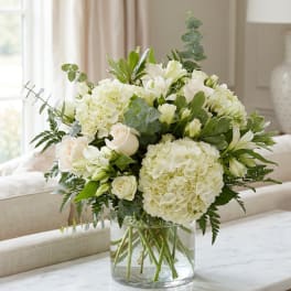 White floral arrangement in a clear glass vase on a table