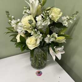 White lilies and roses arranged in a glass vase