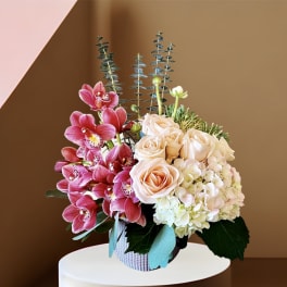 Pink orchids and pale roses arranged in a woven basket