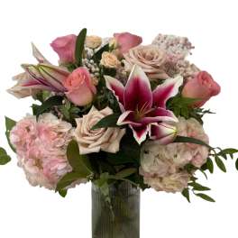 Pink and cream roses with lilies and hydrangeas in a glass vase