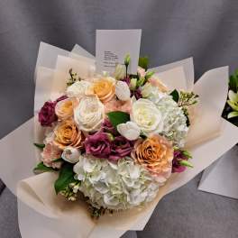 Bouquet of peach, white, and magenta roses with white hydrangeas