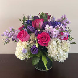 Bouquet of pink and purple roses with white hydrangeas in a glass vase