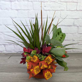 Autumn planter with mixed foliage and a sunflower ribbon bow in a low pot