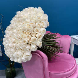 Large bouquet of white roses resting on a pink chair