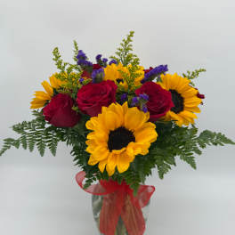 Bouquet of red roses and yellow sunflowers in a glass vase