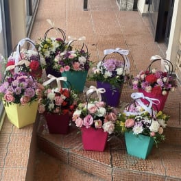 Colorful flower baskets with mixed blooms and ribbon handles arranged on steps