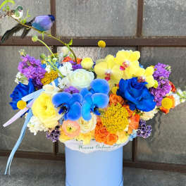 Bright mixed bouquet in a blue hatbox with a bird decoration