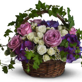 Basket arrangement of pink, white, and purple roses with ivy