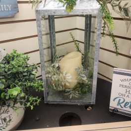 Galvanized metal lantern with ivory candle and white silk flowers with greenery accents.