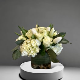 White roses and hydrangeas in a glass vase with greenery