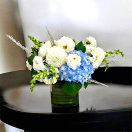 Blue and white floral arrangement in a green glass vase