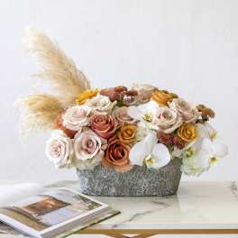 Mixed roses and white orchids in a gray container