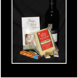 Wine bottle with crackers, cheese, and chocolates on a black background