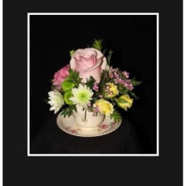 Pink rose arrangement in a teacup with small mixed flowers