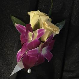 Boutonniere with cream roses and purple orchids on black fabric